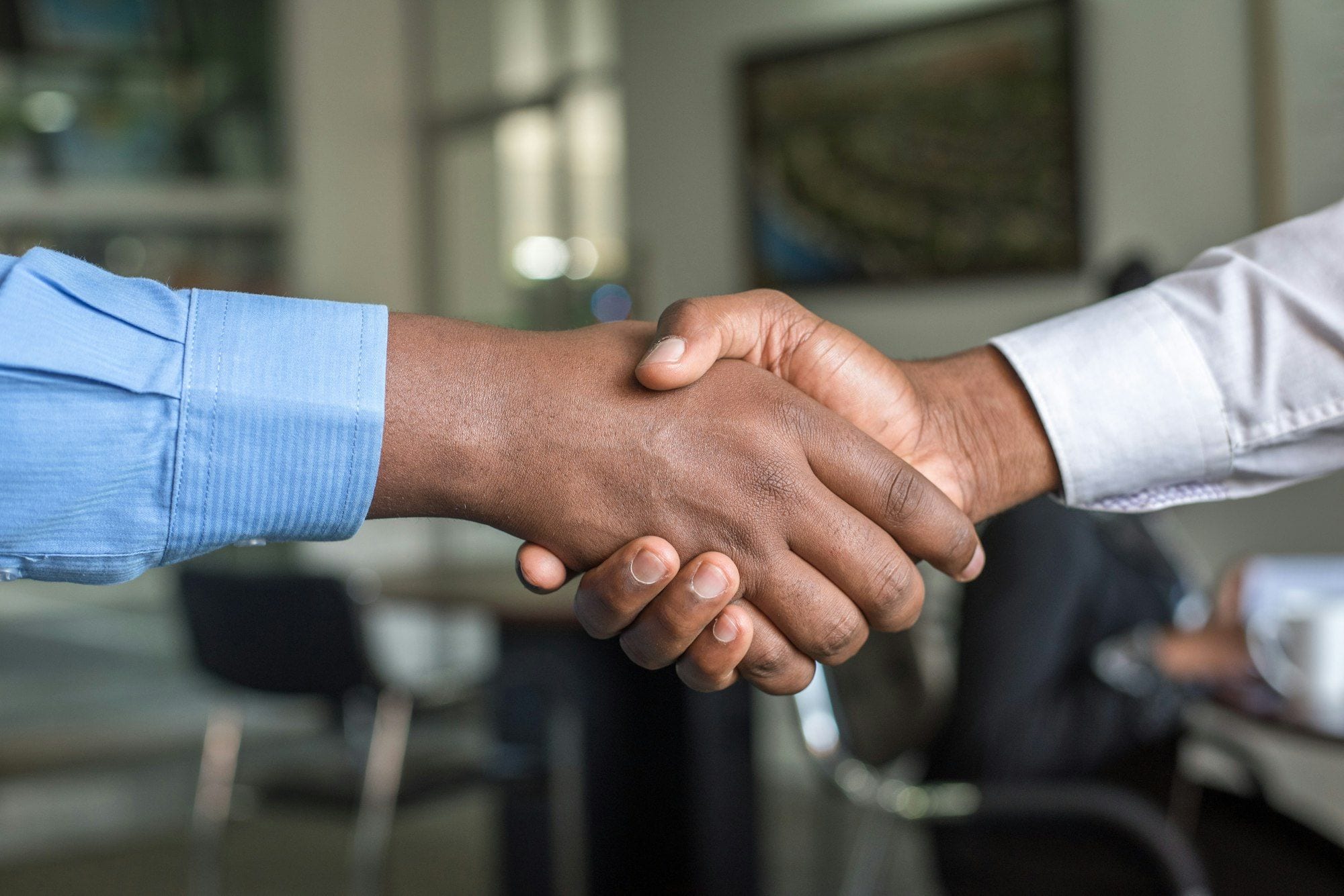 A candidate shaking hands with an interviewer across a desk in an office